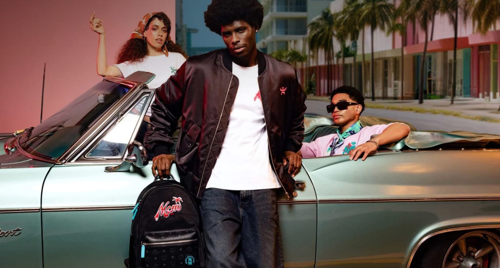 Three young people around a green convertible in a pastel street, one in a satin bomber holding a backpack.