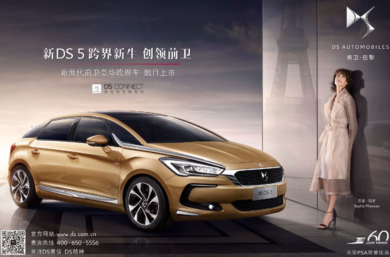 DS Automobiles advertisement with Chinese text: a gold hatchback and a woman in a beige coat in front of the Eiffel Tower.