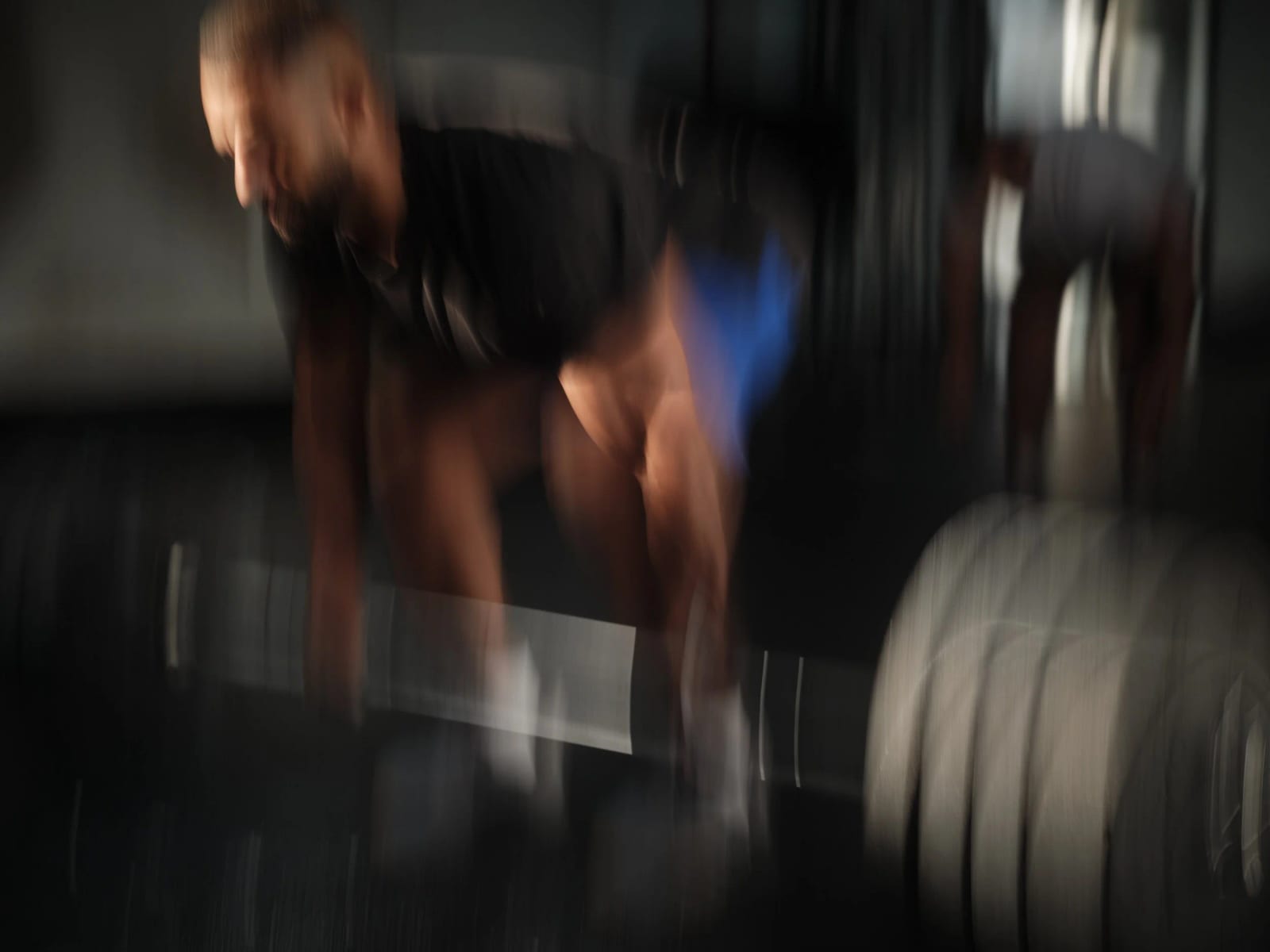 A man lifting a barbell in a gym, the whole frame smeared with motion blur.