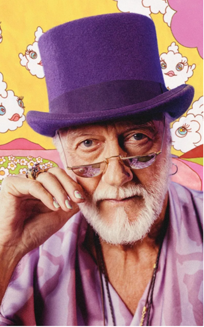 An older man with a white beard in a purple top hat and lilac shirt adjusting his glasses against a psychedelic cartoon backdrop.