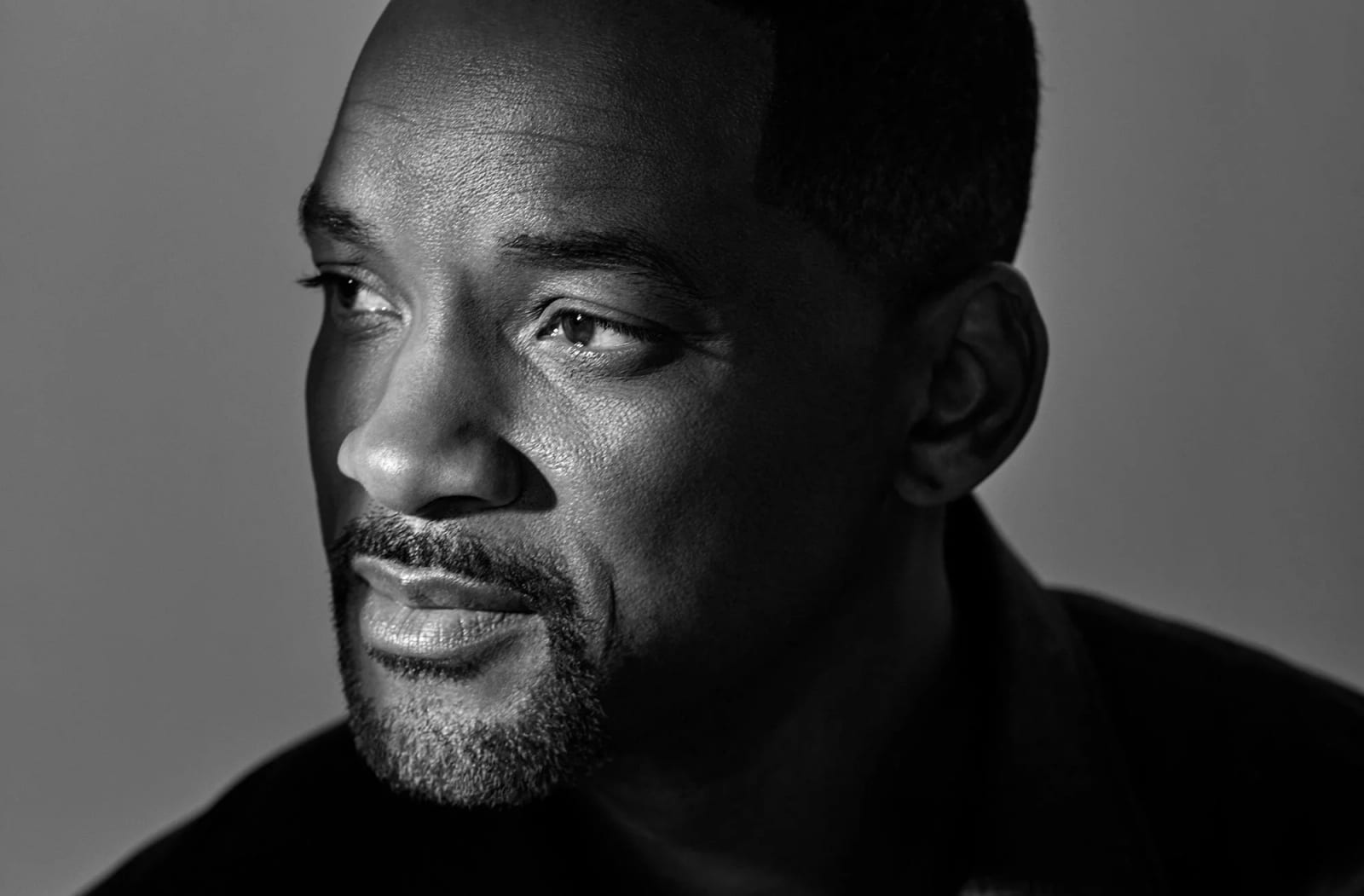Black and white close-up portrait of Will Smith with a goatee, half his face in shadow.