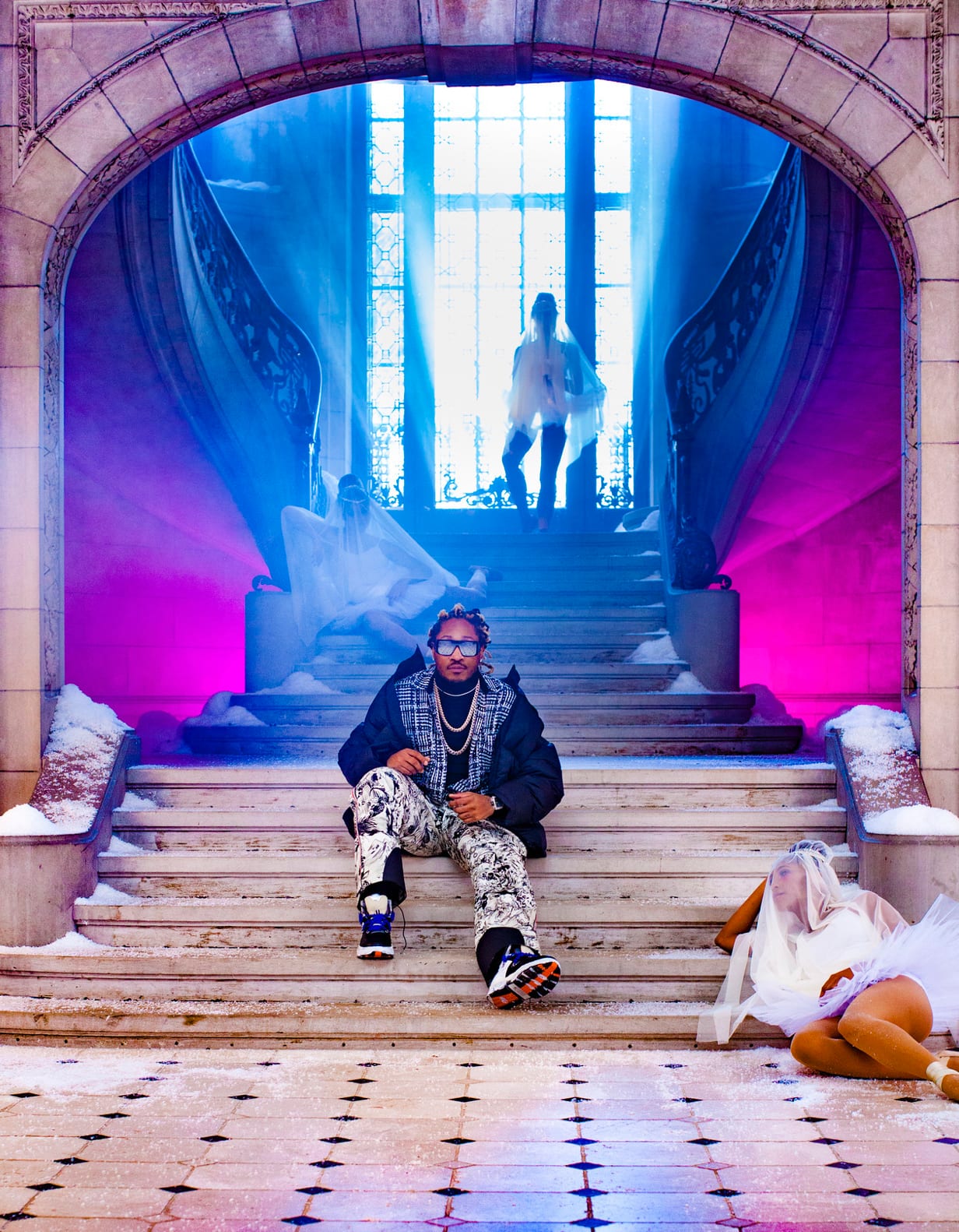A man in a patterned jacket sitting on the steps of a grand staircase lit pink and blue, a woman in a veil lying beside him.