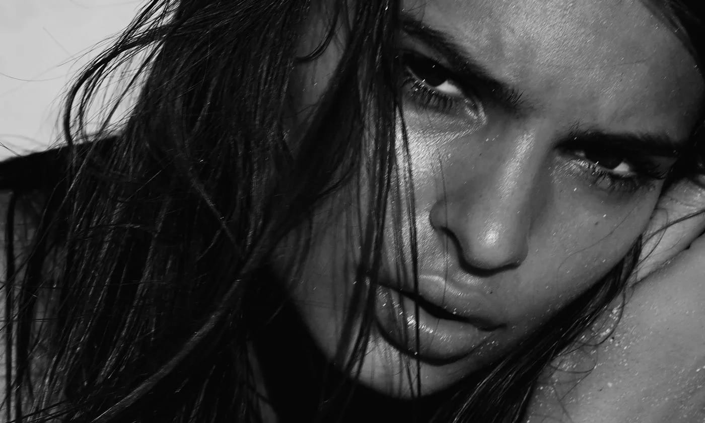 Black and white close-up of a woman with wet hair across her face, staring into the camera.