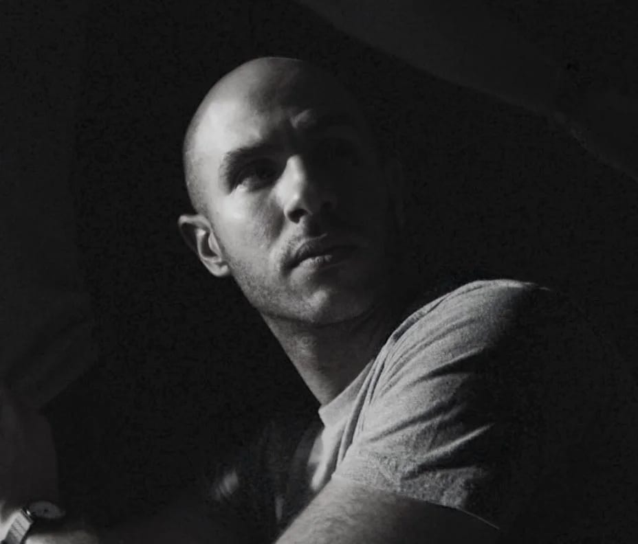 Black and white photograph of Najeeb Tarazi in a T-shirt looking up from the shadows.